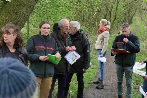 Wandergruppe steht auf einem Waldweg. Frau Kalinowski spricht zu der Gruppe.