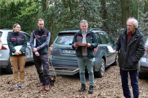 Team der Landesforsten vor geparkten Autos auf Waldparkplatz